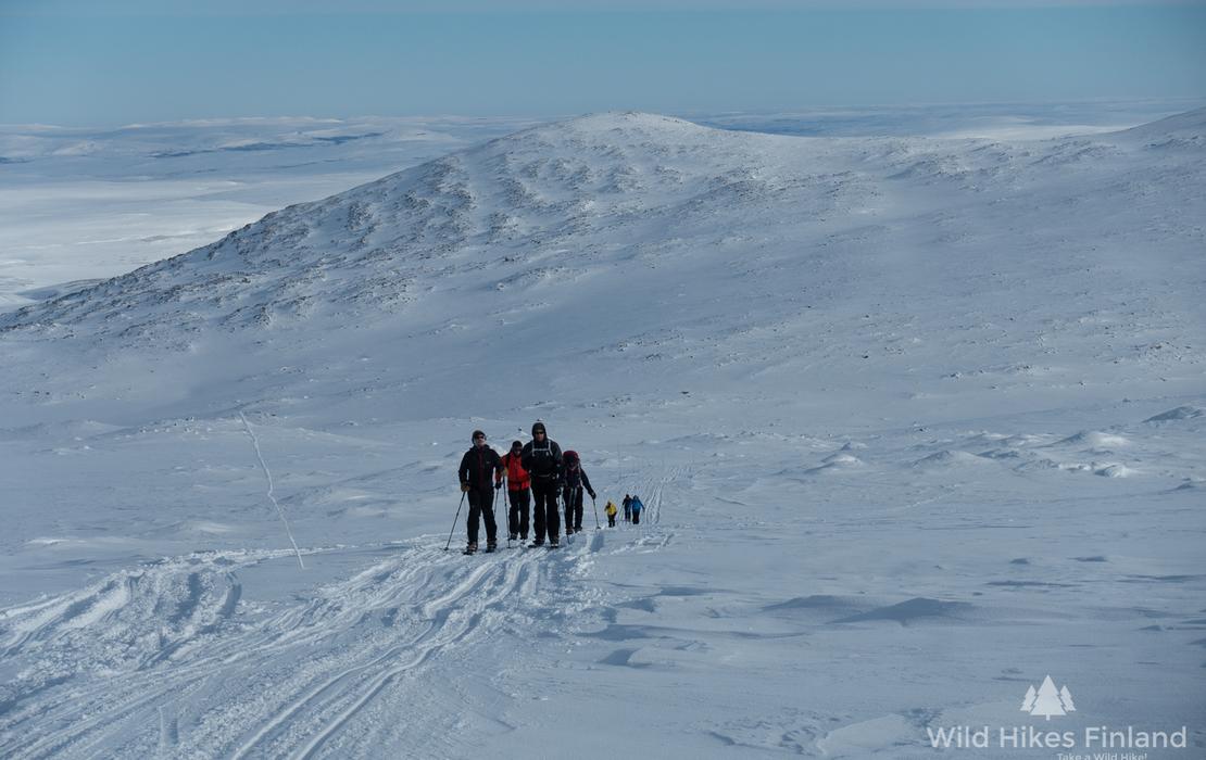 Skiers ascending a mountain slope during an Arctic backcountry expedition.